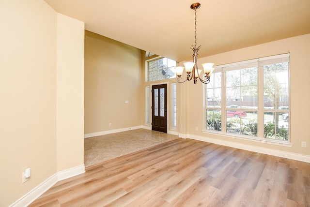 foyer entrance with a chandelier, baseboards, a healthy amount of sunlight, and wood finished floors