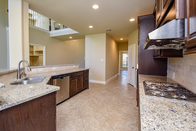 kitchen with a sink, under cabinet range hood, appliances with stainless steel finishes, decorative backsplash, and baseboards