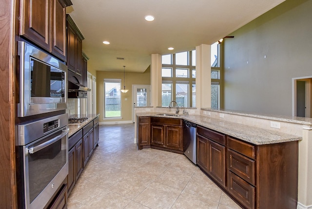 kitchen with light stone countertops, pendant lighting, recessed lighting, appliances with stainless steel finishes, and a sink