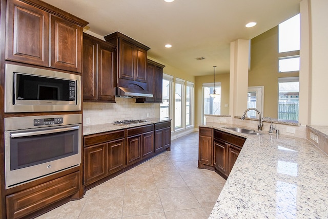 kitchen with light stone counters, light tile patterned floors, a sink, stainless steel appliances, and tasteful backsplash