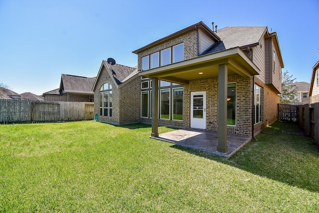 rear view of house featuring brick siding, a patio area, a yard, and a fenced backyard