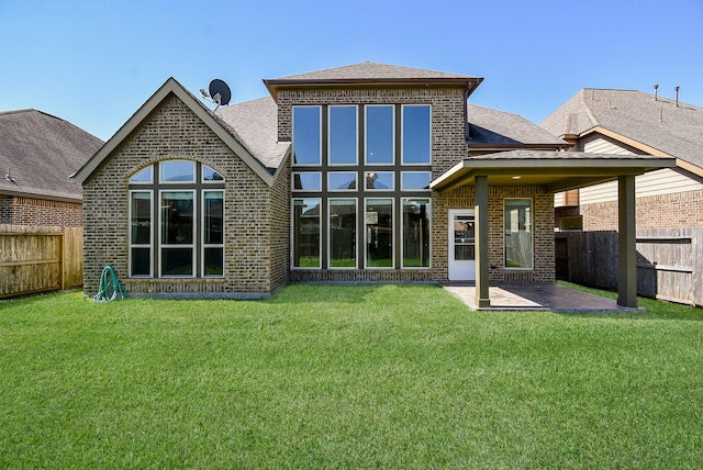 back of house with brick siding, a patio, a fenced backyard, and a lawn
