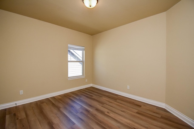 unfurnished room with baseboards and dark wood-style flooring