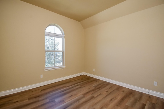 empty room featuring vaulted ceiling, baseboards, and dark wood-style flooring