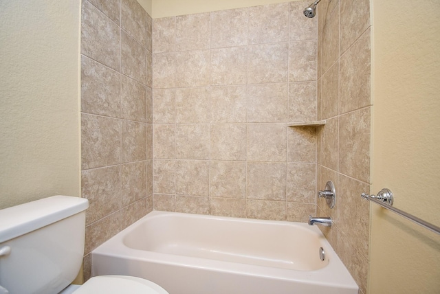 bathroom featuring toilet, shower / bathtub combination, and a textured wall