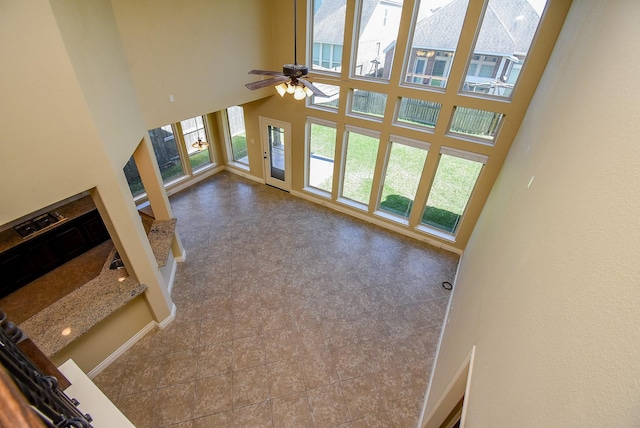 living area with a high ceiling, baseboards, and ceiling fan