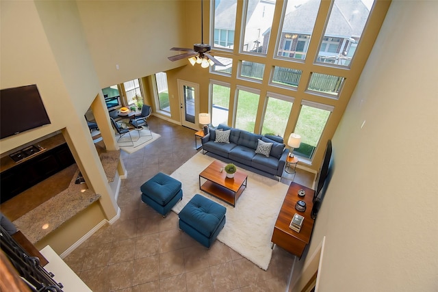 tiled living area featuring a wealth of natural light, baseboards, and a towering ceiling