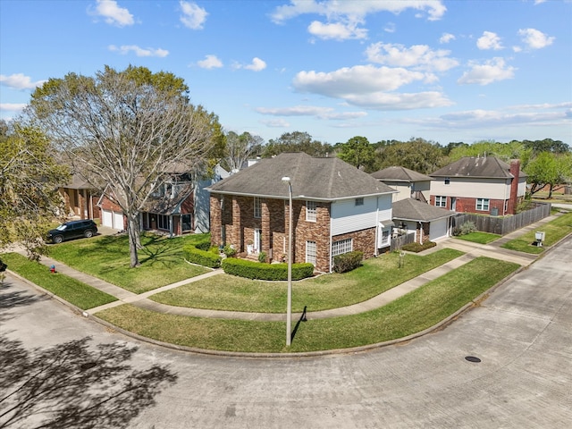 view of front facade featuring brick siding, fence, a residential view, a front yard, and driveway