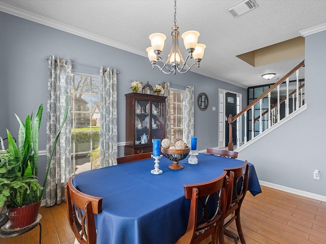 dining space featuring crown molding, wood finished floors, visible vents, and a chandelier