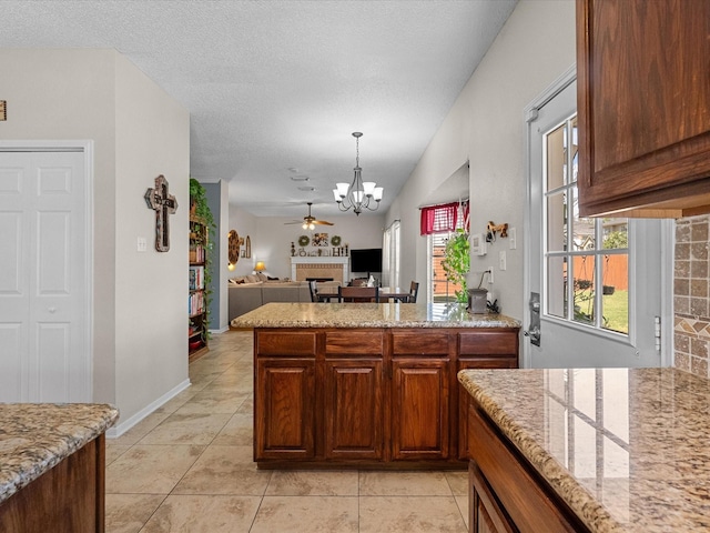 kitchen featuring light stone counters, decorative light fixtures, open floor plan, and a fireplace