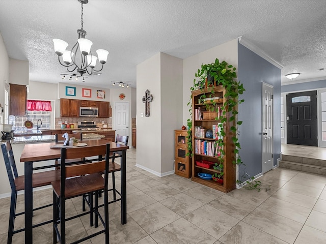 dining room with ornamental molding, a textured ceiling, light tile patterned flooring, baseboards, and a chandelier