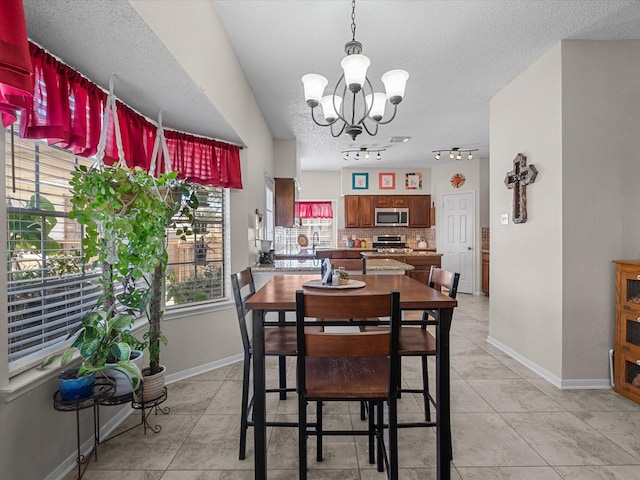 dining room with light tile patterned floors, baseboards, a textured ceiling, and an inviting chandelier