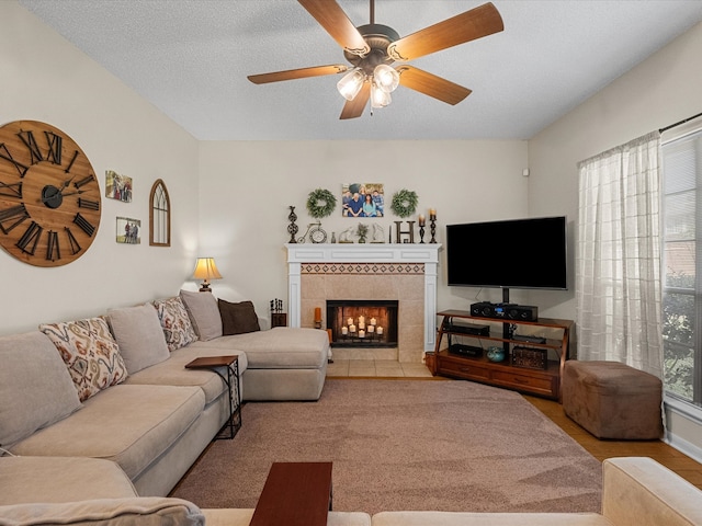 living room with a textured ceiling, a ceiling fan, and a tile fireplace