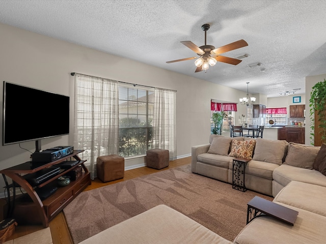 living room with light wood-style flooring, ceiling fan with notable chandelier, visible vents, and a wealth of natural light