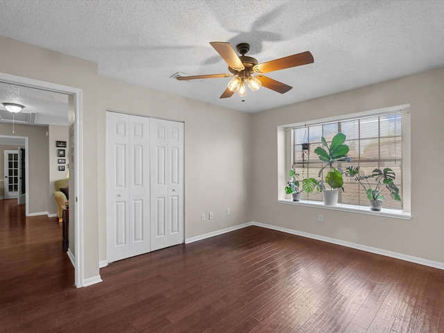 unfurnished bedroom featuring attic access, wood finished floors, a closet, and baseboards