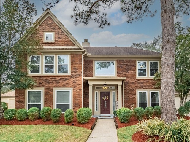 view of front of house with brick siding, a chimney, and a front yard