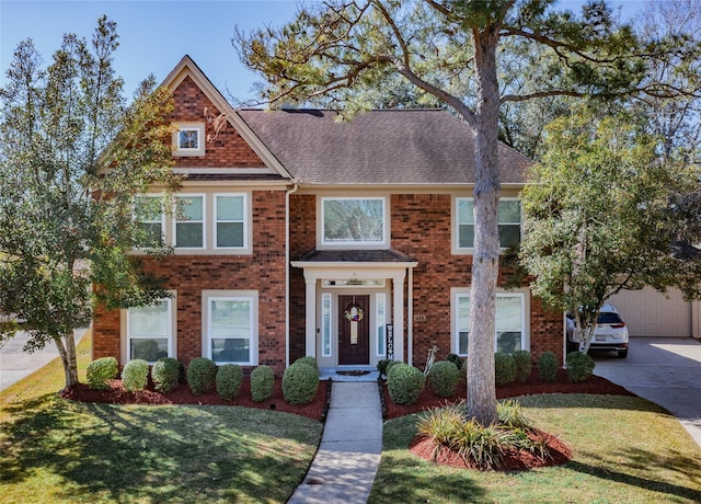 view of front of house featuring driveway, a front lawn, roof with shingles, a garage, and brick siding