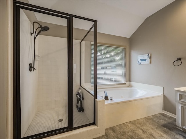 bathroom with a garden tub, a stall shower, wood finished floors, lofted ceiling, and vanity