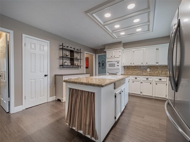 kitchen with white appliances, dark wood finished floors, a center island, and white cabinetry