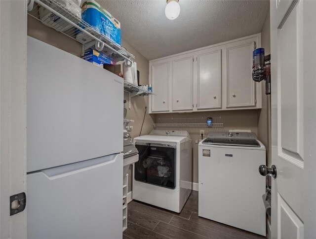 laundry room with a textured ceiling, cabinet space, separate washer and dryer, and wood tiled floor