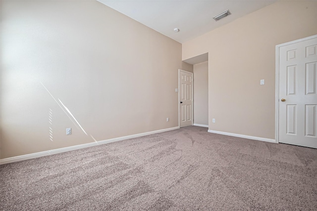 carpeted empty room with visible vents, baseboards, and vaulted ceiling