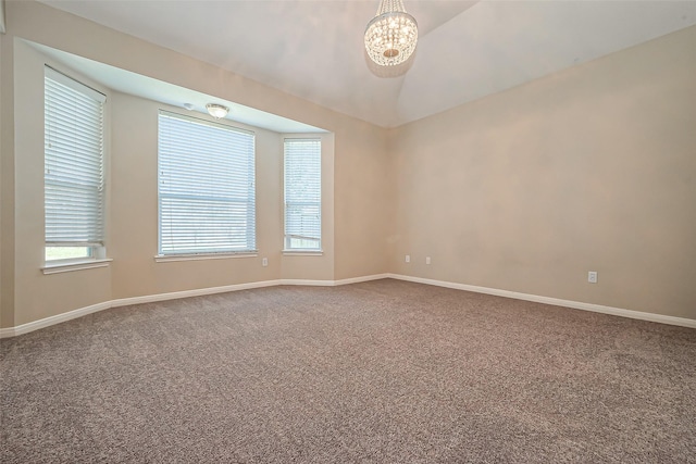 carpeted spare room with a notable chandelier, baseboards, and lofted ceiling