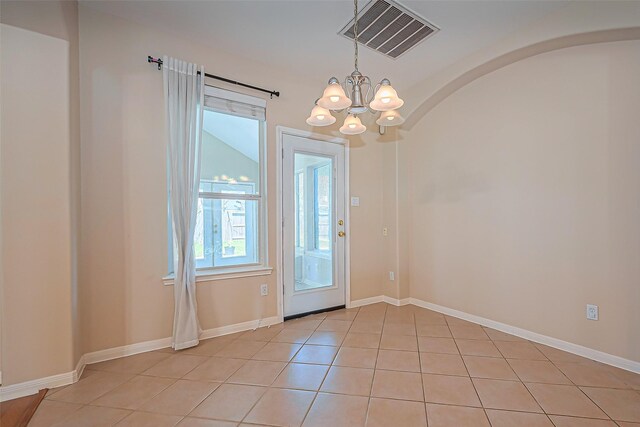 interior space with light tile patterned floors, baseboards, visible vents, an inviting chandelier, and arched walkways