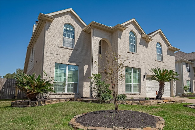 traditional-style house featuring concrete driveway, a garage, fence, and a front yard