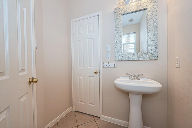 bathroom with tile patterned flooring, baseboards, and a sink