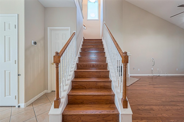 stairs with tile patterned floors, high vaulted ceiling, a ceiling fan, and baseboards