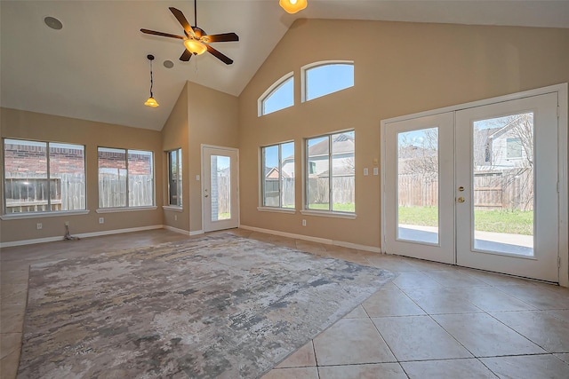 unfurnished living room featuring light tile patterned floors, french doors, plenty of natural light, and high vaulted ceiling