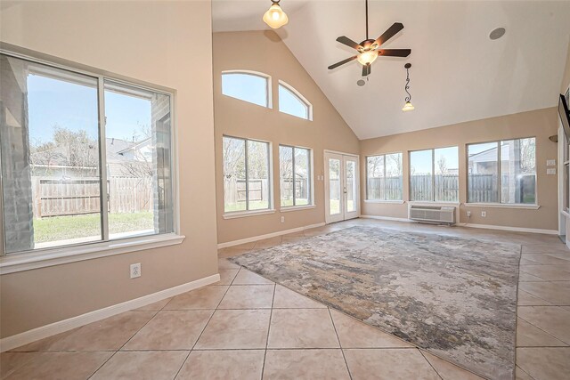 unfurnished sunroom featuring a ceiling fan, an AC wall unit, a healthy amount of sunlight, and lofted ceiling