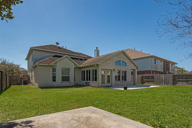 rear view of house with a yard, a fenced backyard, a chimney, and a patio area