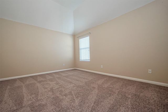 carpeted empty room featuring baseboards and lofted ceiling