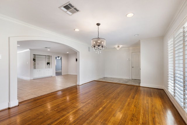 empty room featuring a notable chandelier, arched walkways, visible vents, and wood-type flooring