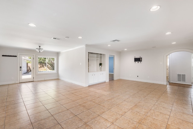 spare room featuring arched walkways, visible vents, and baseboards