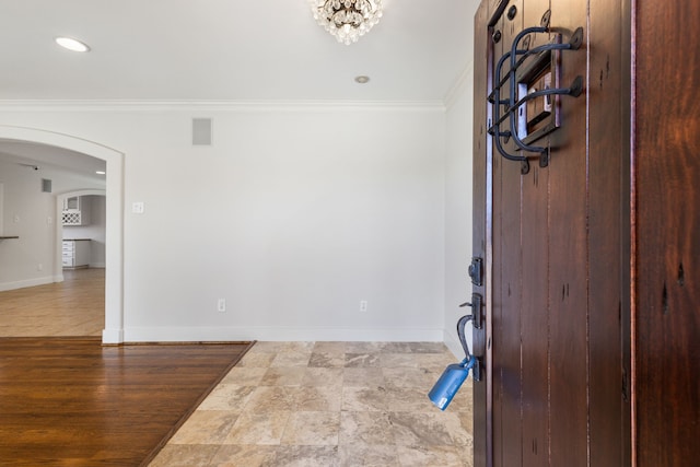 entrance foyer featuring arched walkways, visible vents, crown molding, and baseboards