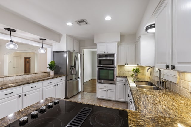 kitchen with visible vents, a sink, appliances with stainless steel finishes, white cabinets, and decorative backsplash