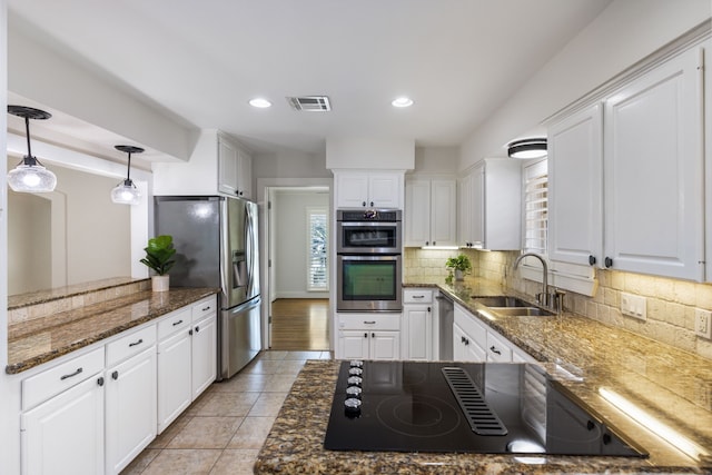 kitchen featuring visible vents, backsplash, white cabinets, stainless steel appliances, and a sink