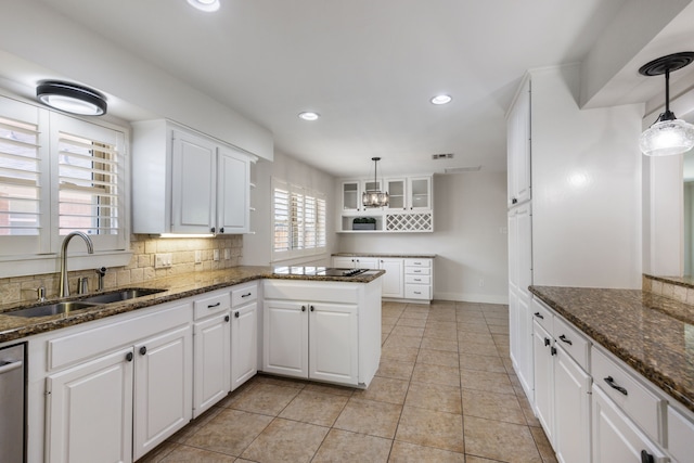 kitchen featuring tasteful backsplash, a peninsula, white cabinetry, and a sink