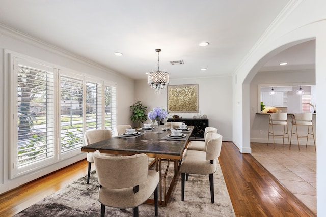 dining room with visible vents, wood finished floors, recessed lighting, arched walkways, and crown molding