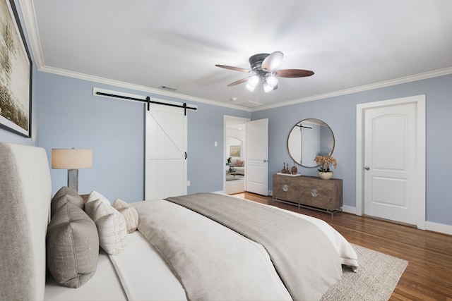 bedroom with ornamental molding, a barn door, and wood finished floors