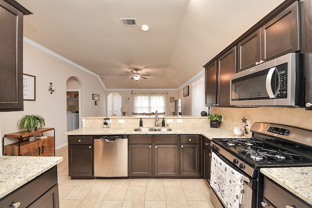 kitchen with dark brown cabinetry, washer and dryer, appliances with stainless steel finishes, and a sink