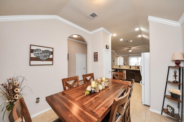 dining room with arched walkways, visible vents, crown molding, and vaulted ceiling