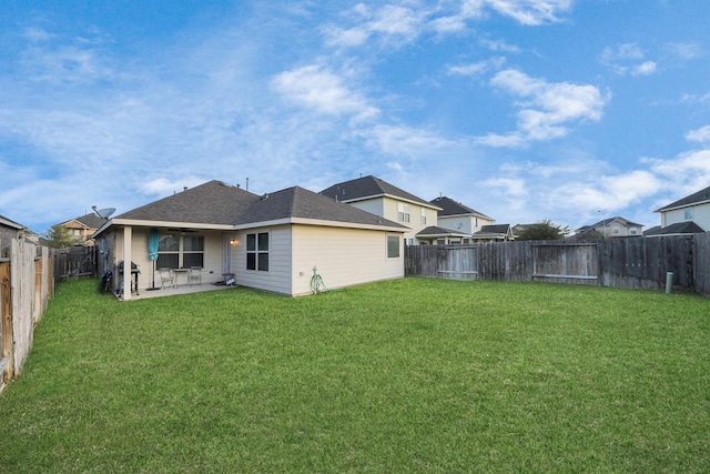 rear view of property featuring a shingled roof, a lawn, a fenced backyard, and a patio area