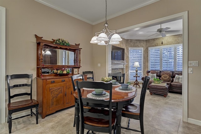 dining room featuring light tile patterned floors, ornamental molding, ceiling fan, and a premium fireplace