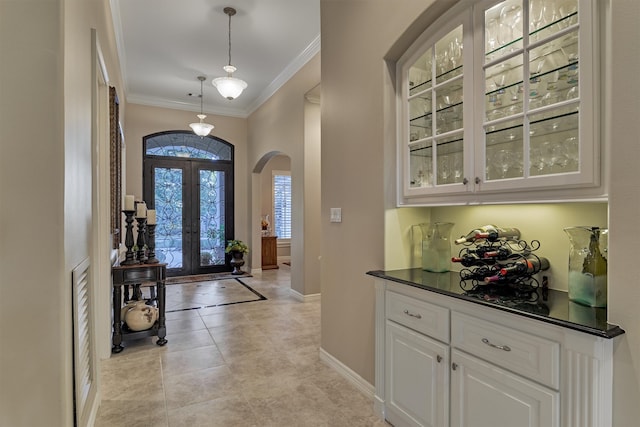 entrance foyer with crown molding, baseboards, french doors, light tile patterned flooring, and arched walkways