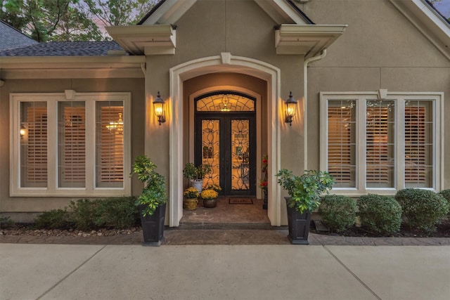 doorway to property featuring roof with shingles and stucco siding