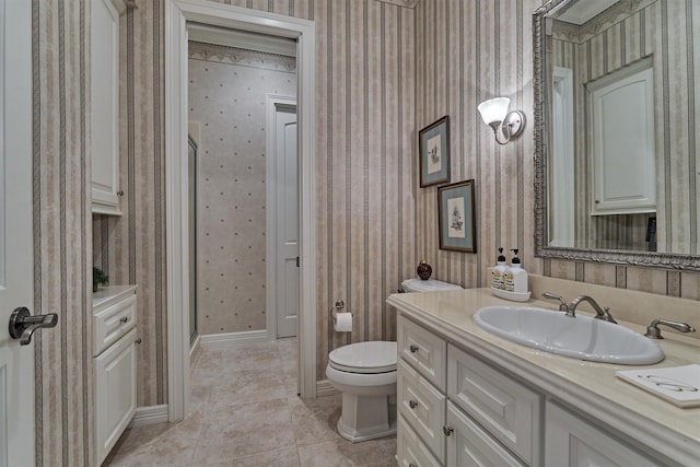 full bath featuring wallpapered walls, baseboards, toilet, a stall shower, and vanity