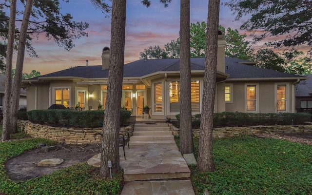 ranch-style home with stucco siding, french doors, and a chimney